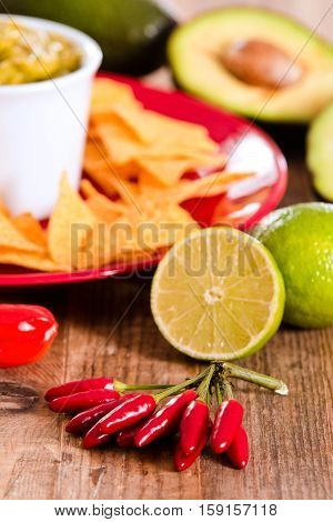 Guacamole and nacho chips on red dish.