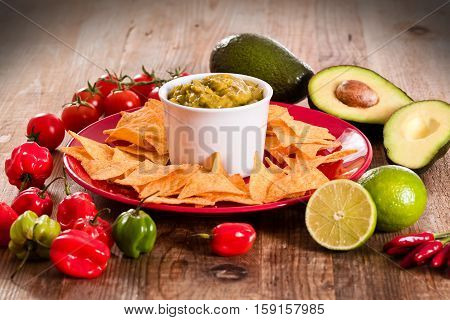 Guacamole and nacho chips on red dish.