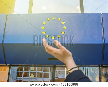 Elegant Woman hand trying to hold the stars of European Union insignia in front of the Council of Europe entrance