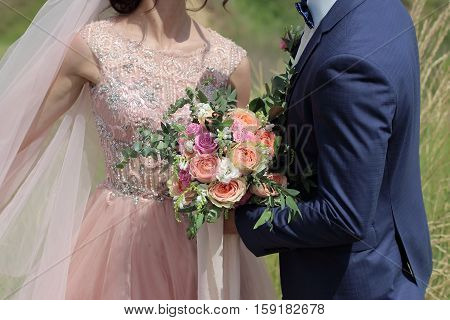 Beautiful bridal bouquet in hands of the bride. Wedding bouquet of peach roses by David Austin single-head pink rose aqua eucalyptus ruscus gypsophila