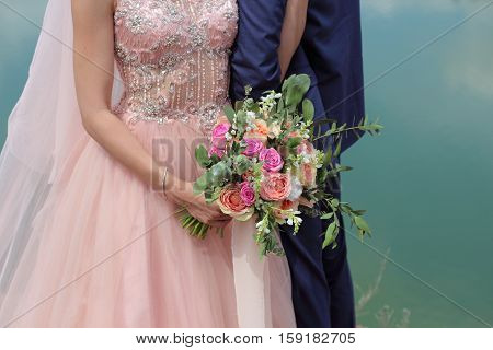 Bride holding a beautiful bridal bouquet. Wedding bouquet of peach roses by David Austin single-head pink rose aqua eucalyptus ruscus gypsophila