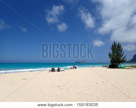 HONOLULU HAWAII - APRIL 25: People hang out on Waimanalo Beach as gentle wave lap on on shore looking towards Rabbit island and Rock island on a nice day Oahu Hawaii. April 25 2016.