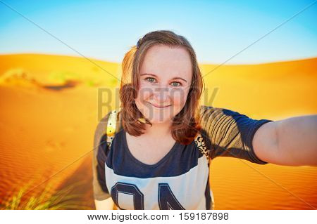 Happy smiling tourist taking selfie with sand dunes in Sahara desert at Erg Chebby Merzouga Morocco