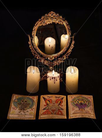 Vertical vintage still life with divination rite objects - mirror, candles and the tarot cards. Halloween concept, black magic ritual or spell with occult and esoteric symbols