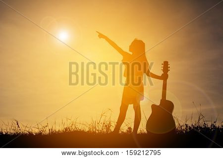Silhouette happy girl playing guitar at the sky sunset happy time in holiday vintage tone
