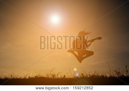 Silhouette happy girl playing guitar at the sky sunset happy time in holiday vintage tone