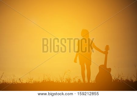 Silhouette happy girl playing guitar at the sky sunset happy time in holiday vintage tone