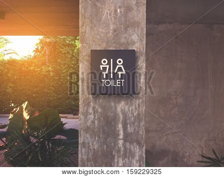 Unisex restroom or toilet label on concrete post.