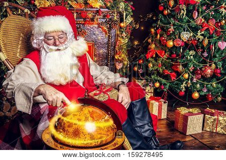 Christmas, tourist trip concept. Santa Claus at his home beautifully decorated for Christmas making plans of travelling around the planet. Christmas time. Time for miracles.