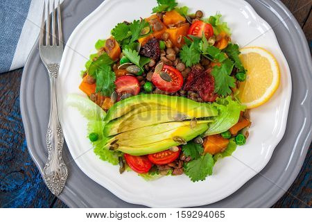 Salad with baked sweet potatoes avocados lentils dried tomatoes cilantro pumpkin seeds and oil. Perfect for the detox diet or just a healthy meal. Love for a healthy raw food concept.