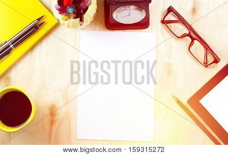 Office table desk top view with tablet PCa cup of coffee pen pencil glasses clock book and blank paper on wooden background. with warm light effect in composition