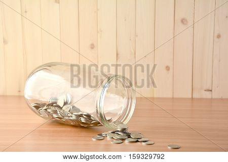 Coin spilled from a big glass bottle .