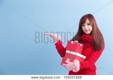 beauty woman take gift and show something in christmas isolated on blue background asian