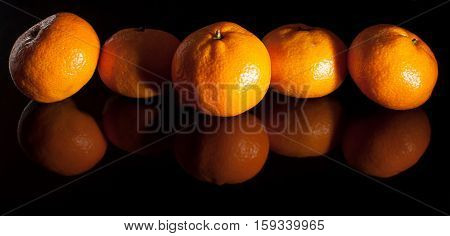Group Of Mandarins With Reflection On Black Background