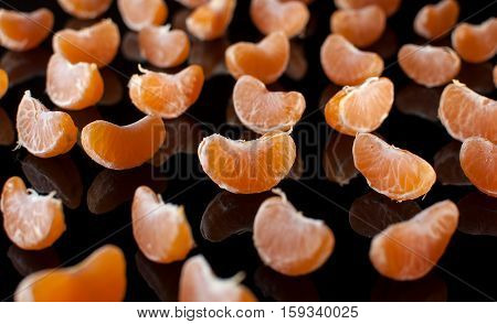 Group Of Mandarin Slices With Reflection On Black Background