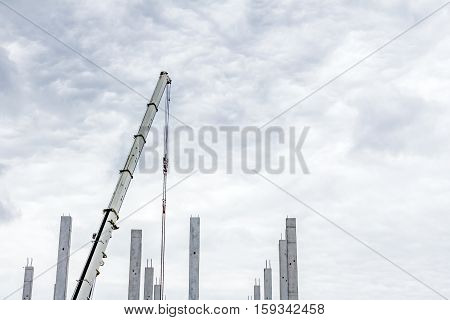 Mobile crane is operating to assembly concrete joist on new edifice.