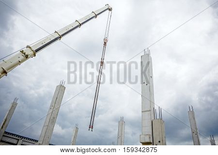 Mobile crane is operating to assembly concrete joist on new edifice.