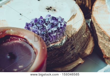 Purple and gemmy amethyst stone with brown candle on wood background as rough ametist crystals . magic stone talisman indian mood esoterics oriental concept.