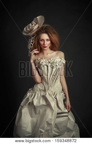 Beautiful redhead girl in elegant paper dress. Sensual image with bright makeup. Beauty model