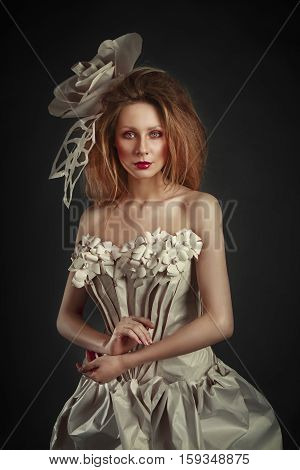 Beautiful redhead girl in elegant paper dress. Sensual image with bright makeup. Beauty model