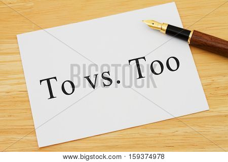 Learning to use proper grammar A white card on a desk with a pen with words To vs Too