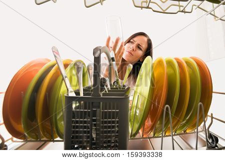 Young Unhappy Woman Looking At Clean Glass In Dishwasher