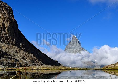 The woman hiking to Riffelsee lake in front of Matterhorn and cloud during summer Zermatt Switzerland.
