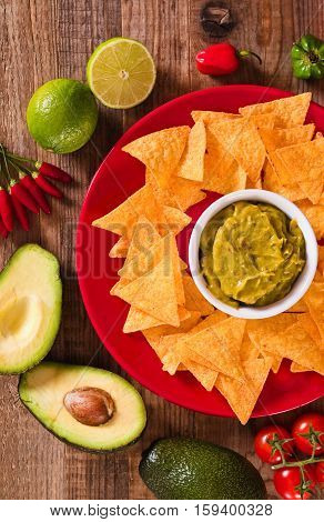 Guacamole and nacho chips on red dish.