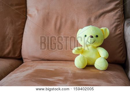 Yellow bear doll sitting on couch, Soft yellow bear doll sitting on sofa