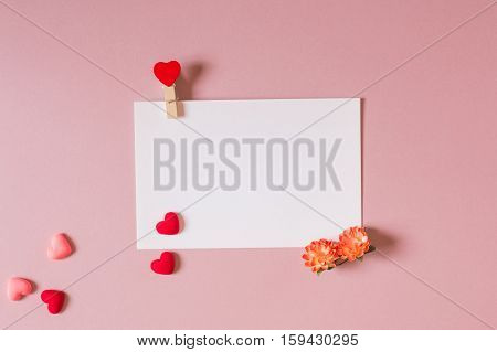 Valentine day composition: stationery / photo template with clamp spring flowers and small hearts on light pink background. Top view.