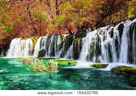 Waterfall And Azure Lake With Clear Water Among Fall Woods