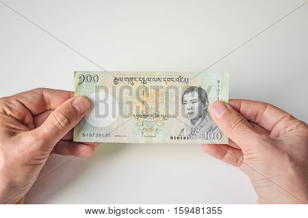 Man Holding Hundred Bhutanese Ngultrum Banknote In His Hands