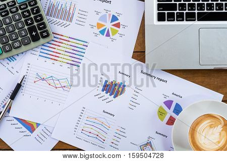 Office desk working table with pen laptop computer business graph or analysis chart and calculator cup of coffee.Top view with copy space.Office supplies and gadgets concept.