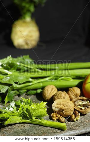 Ingredients for Waldorf salad - celery apples walnuts - fresh and healthy vegetables on granite board.