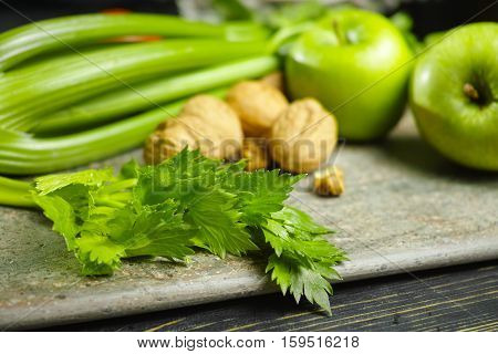 Ingredients for Waldorf salad - celery apples walnuts - fresh and healthy vegetables on granite board.