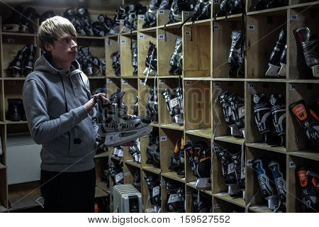Saint-Petersburg Russia - December 2 2016: Urban outdoor ice rink in the park. rental item Shelves with skates. Man gives skates.
