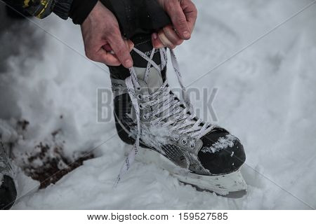 Saint-Petersburg Russia - December 2 2016: Urban outdoor ice rink in the park. Tying skates before going on the ice.
