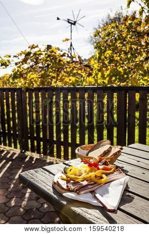 Brettljause traditional wooden plate with cold cuts only with self-made food on terrace in vineyard on western Styria vine route