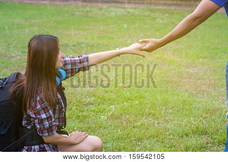 Woman sitting on the grass reaching to shake the hand of man. helping hand and love concept.