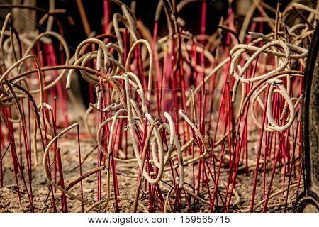 Incense sticks burning down in a pot in a asian buddhist temple