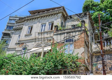The old abandoned house with peeling paint and green trees in front of it at Santa Teresa district of Rio de Janeiro, Brazil
