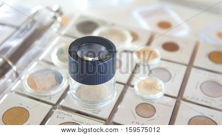 Round magnifying glass on album with coins from different countries - Numismatic scene