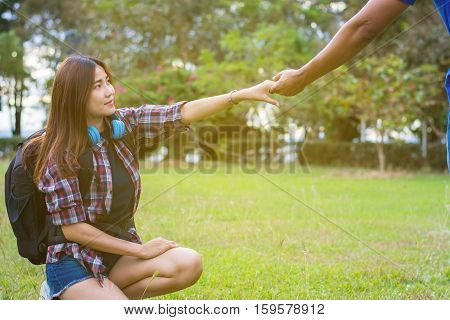 Woman sitting on the grass reaching to shake the hand of man. helping hand and love concept.