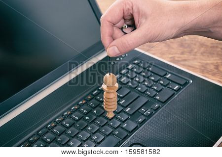 Hand with pendulum dowsing over laptop pc to check its quality, dangerous influence or radiation