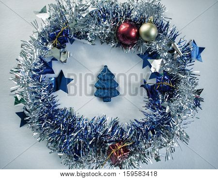Vintage Christmas photo. Blue ribbon wreath and fir tree toy toned photo. Blue Christmas tree decor in wreath. Christmas card background or banner template. Christmas decor flat lay on white backdrop