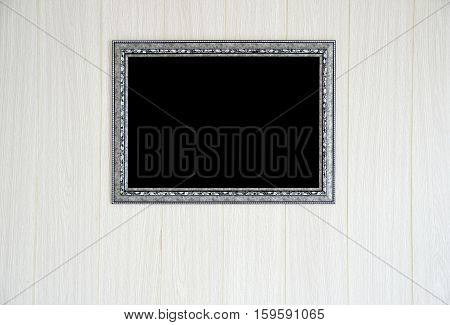 Ornate metal black and white blank frame at the wooden wall with clipping path for the inside