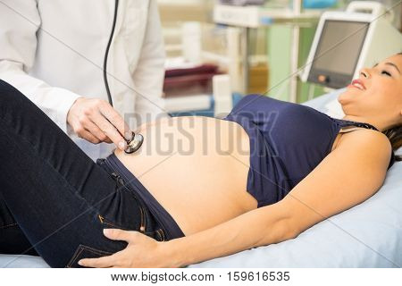 Doctor Examining Belly Of Pregnant Woman