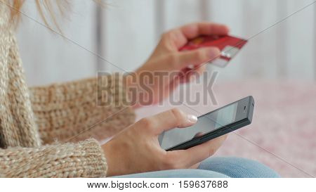 Young woman buying goods from the internet and entering number security code from credit card on smartphone. Online, technology and internet concept