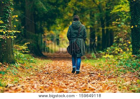 Woman With Shoulder Bag Walking On Path In Autumn Forest.