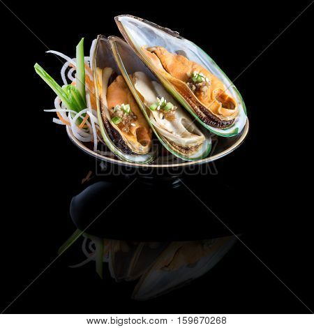 sashimi with mussels in a black plate. On a black background with reflection.